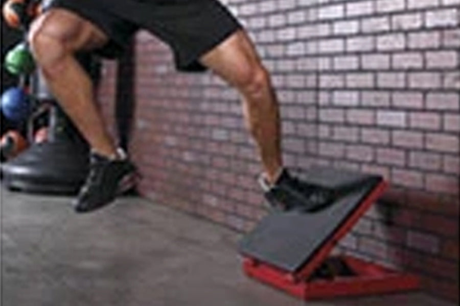 Athlete performing lateral jump on red and black plyo box against brick wall