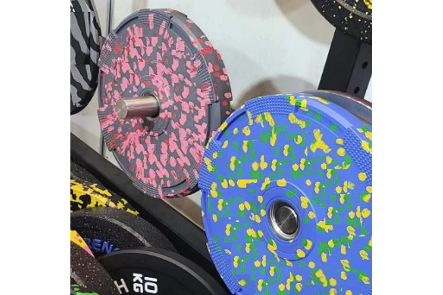 Colorful rubber bumper plates with fleck pattern design, including pink and gray plate with metal center collar and blue plat