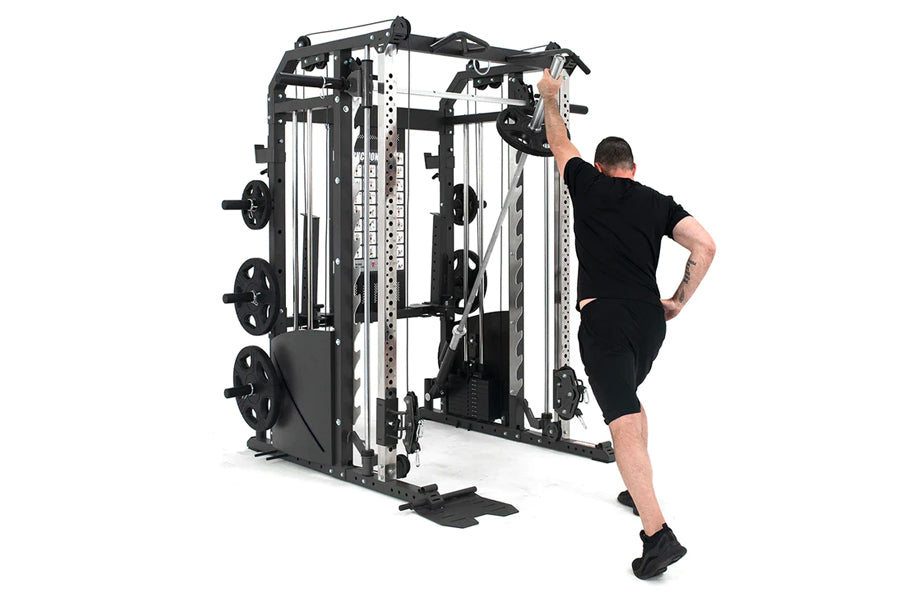 Man in black shirt and shorts using black and silver Smith machine with cable crossover attachment, on white background