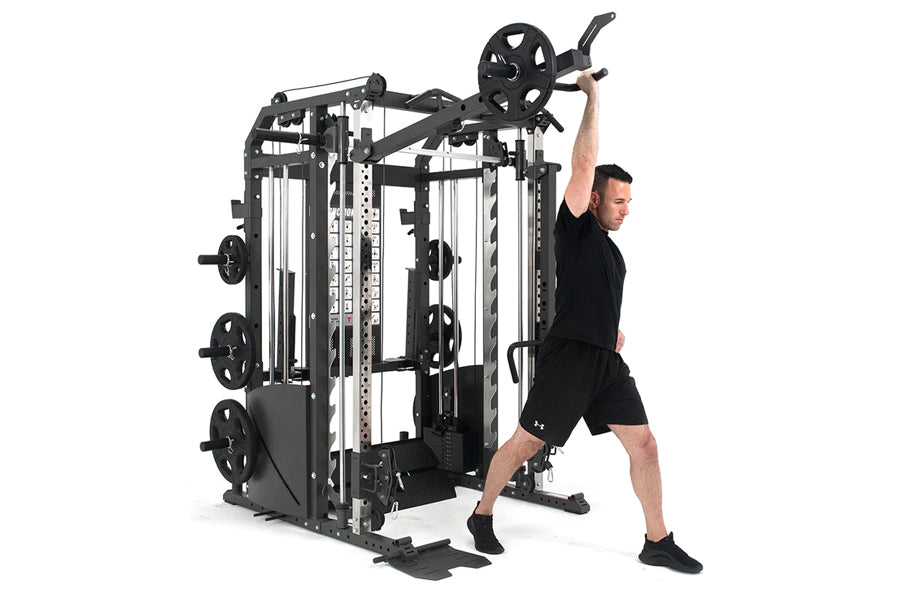 Black and white multi-station gym equipment with cable system and weight plates, demonstrated by man in black athletic wear p