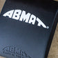 Navy blue AbMat core training pad with white ABMAT logo and curved design, flat lay on concrete background