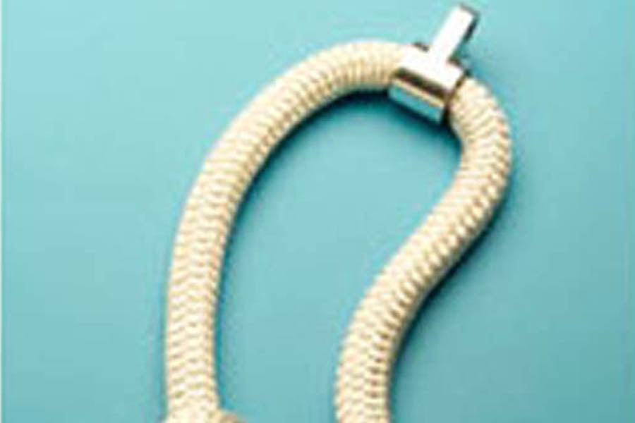 Cream-colored textured rope bracelet with silver toggle clasp on turquoise background