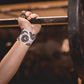 White athletic tape with black circular emblem pattern worn on wrist, gripping metal bar