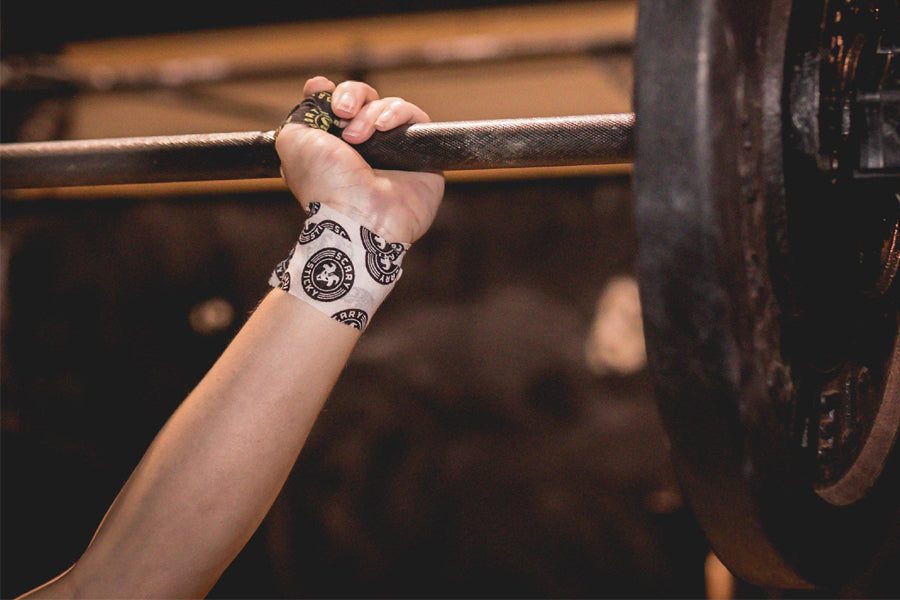 White athletic tape with black circular emblem pattern worn on wrist, gripping metal bar