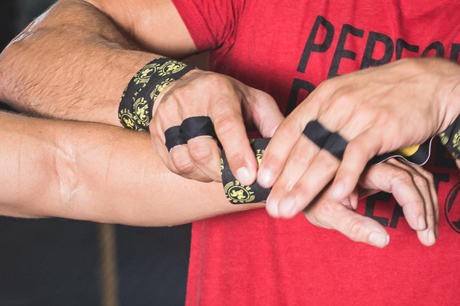 Black and gold athletic tape worn on fingers and wrist by model in red shirt
