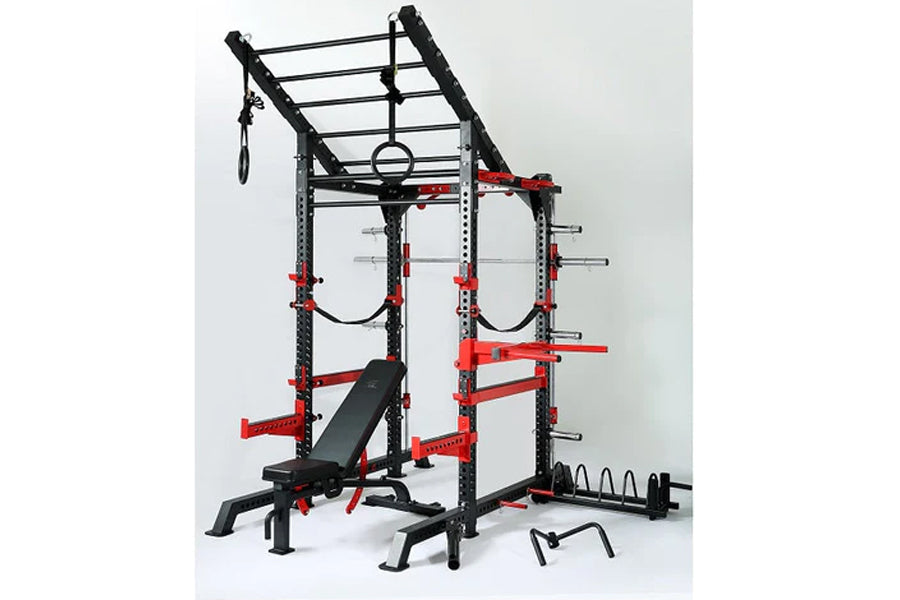 Black and red metal squat rack cage with multi-grip pull-up bar, weight plate storage, bench seat, and accessories on white b