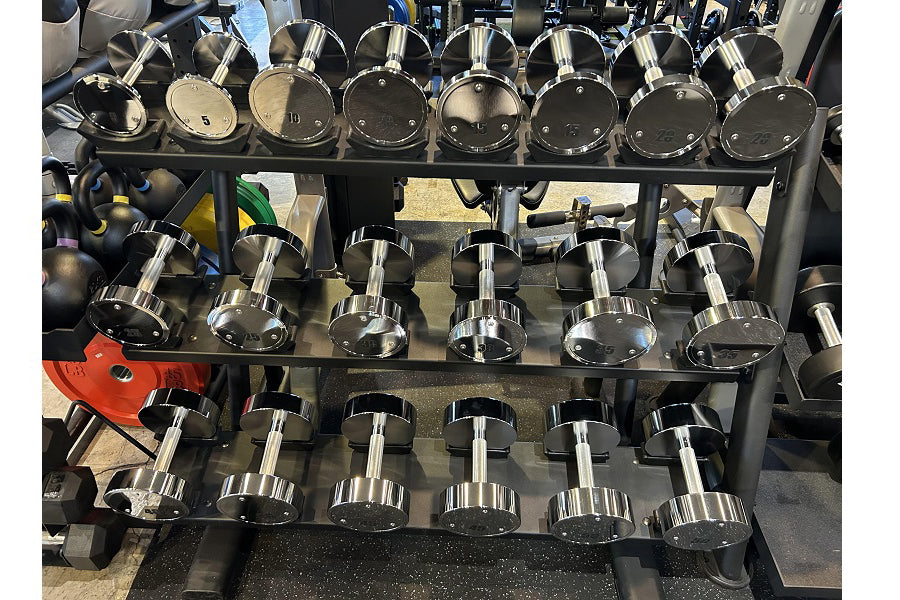 Chrome dumbbell set with multiple weights arranged on black tiered storage rack, displaying pairs of dumbbells with silver ha