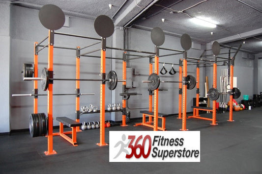 Warrior Commercial Pro Rig System with orange steel frame, black pull-up bars, weight plates, and dumbbells in gym setting
