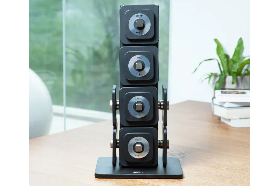 Warrior D22.5 adjustable dumbbells stacked vertically on black base with carrying handles, displayed on wooden desk