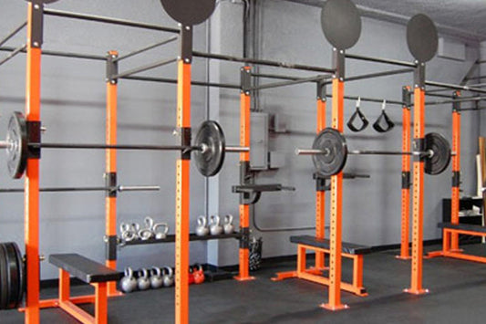 Warrior Endless Pull-Up Rig with bright orange metal frame, black pull-up bar, suspension straps, and weight plates in gym se