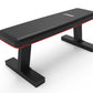 Black and red flat weight bench with padded seat, sturdy black frame base, on white background