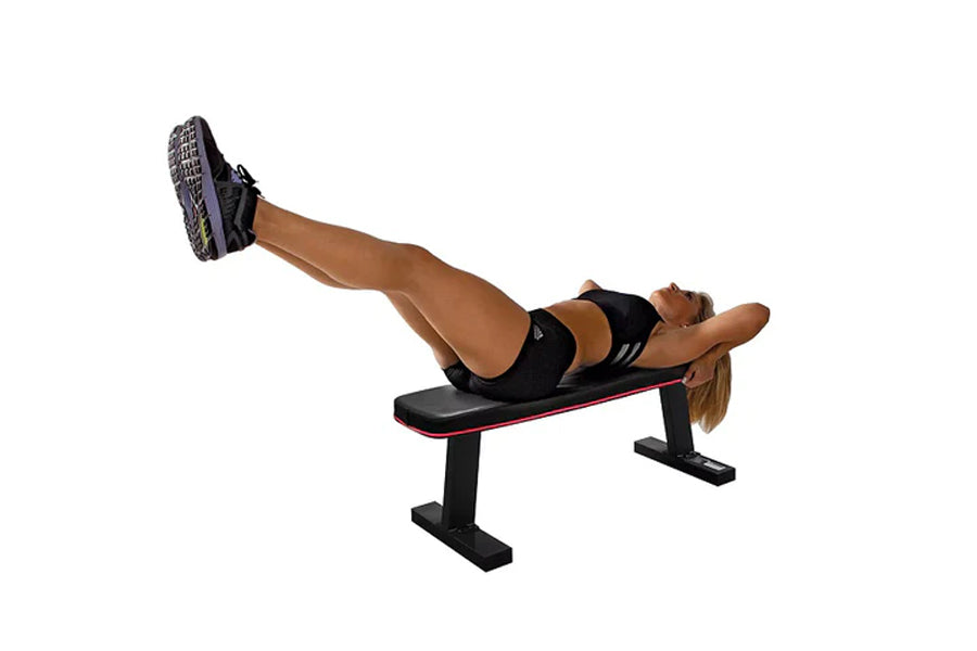 Woman performing leg raise exercise on black flat bench with red trim against white background