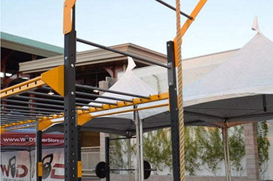 Warrior Flying Pull Up Attachment with yellow and black metal frame mounted on outdoor training rig