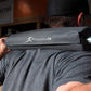 Black foam barbell squat pad with silver metal bar, worn on shoulders by man lifting weights