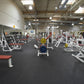 Warrior Interlocking Rubber Gym Flooring Tiles in speckled black, installed in commercial fitness facility with exercise equi