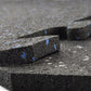 Stacked interlocking rubber gym flooring tiles in speckled black with blue markings and white fleck detail