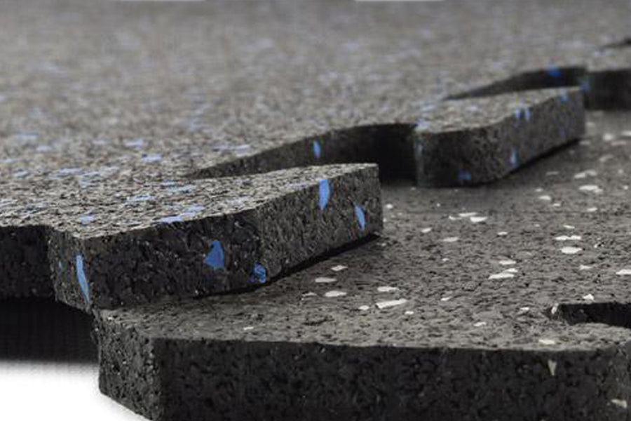 Stacked interlocking rubber gym flooring tiles in speckled black with blue markings and white fleck detail