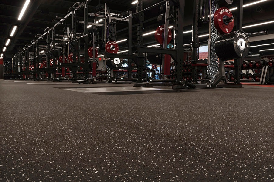 Warrior Interlocking Rubber Gym Flooring Tiles in speckled black with red and white flecks, installed in commercial gym space