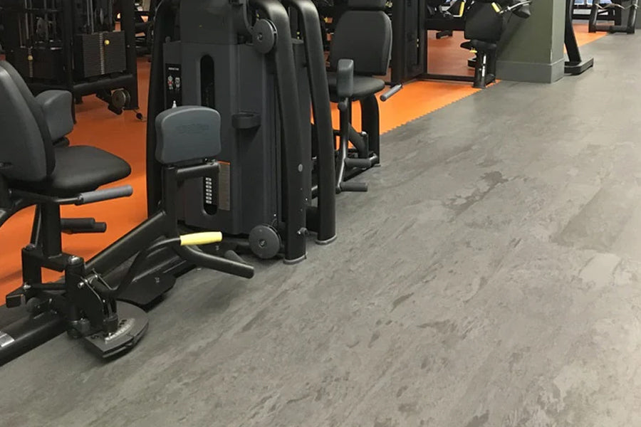 Warrior Marble Interlocking Gym Tile Flooring in Pine gray shown installed in gym with exercise equipment