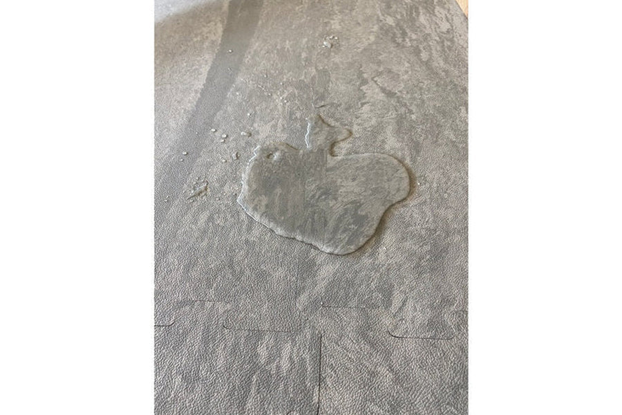 Warrior Marble Interlocking Gym Tile Flooring in sand color with wet footprint impression on textured surface