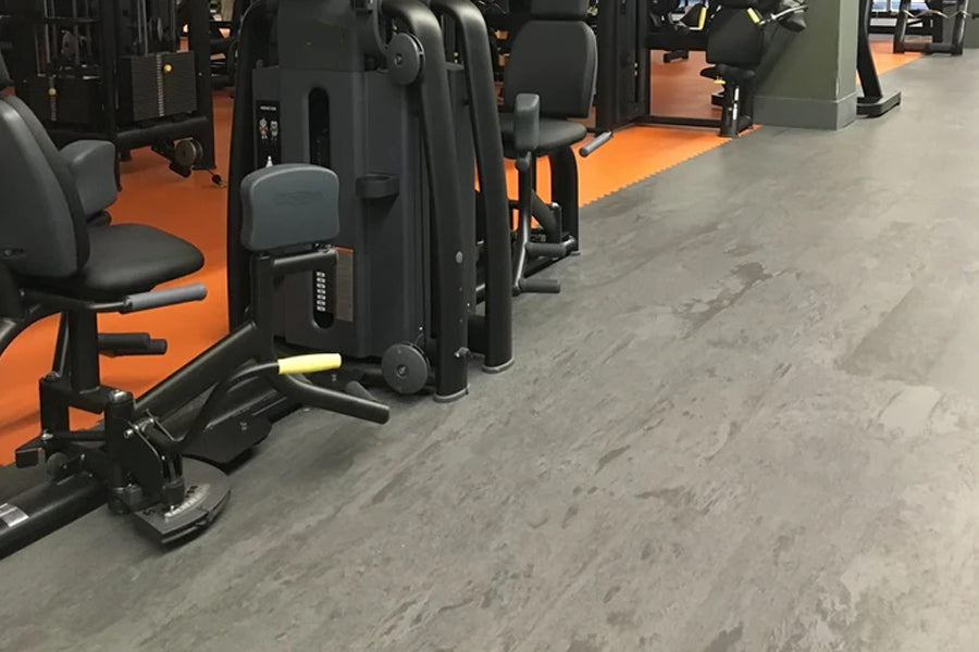Warrior Marble Interlocking Gym Tile Flooring in smoke grey shown in fitness facility with orange and black equipment