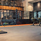 Warrior Marble Interlocking Gym Tile Flooring in stone grey installed in modern gym with equipment and orange accent strips