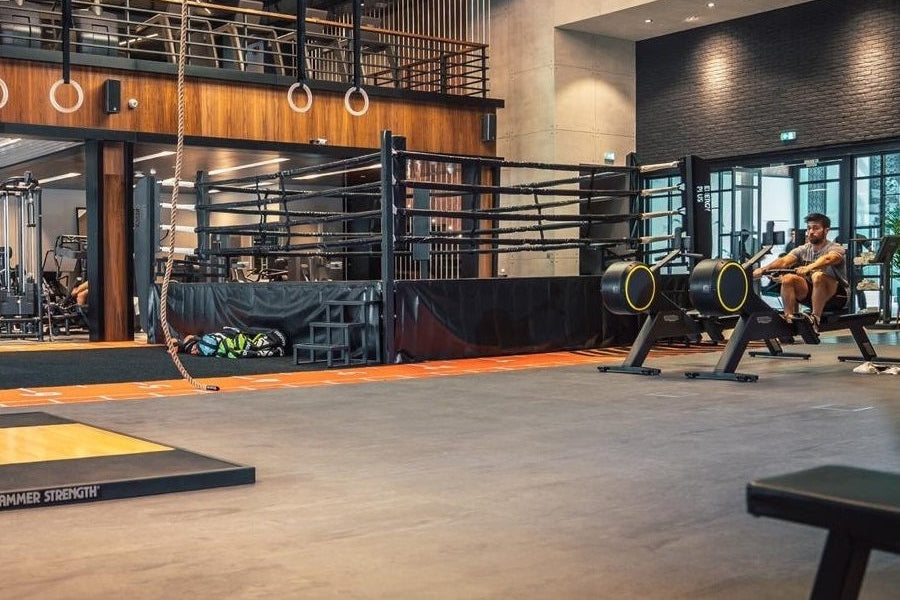 Warrior Marble Interlocking Gym Tile Flooring in stone grey installed in modern gym with equipment and orange accent strips
