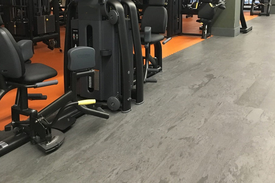 Warrior Marble Interlocking Gym Tile Flooring in stone grey, installed in fitness facility with exercise equipment