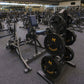Gym floor view showing interlocking rubber tiles with black weight plates and stationary bikes in fitness facility