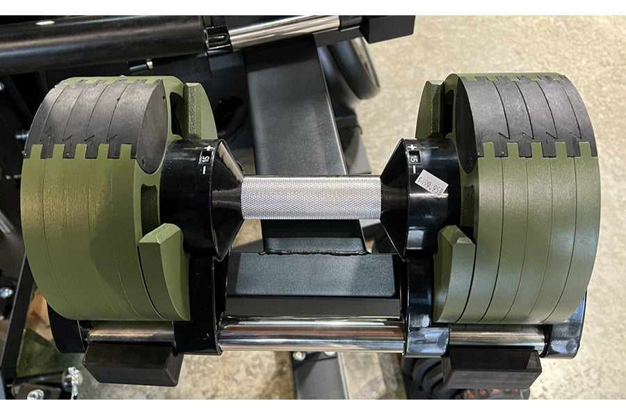 Adjustable dumbbell with olive green weight plates and black handle, displayed on stand showing 50lb/80lb configuration
