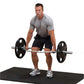 Male model wearing gray v-neck t-shirt and black shorts performing barbell deadlift with chrome hex bar on black platform