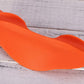 Bright orange foam squat pad with curved design and handles, displayed on whitewashed wood background