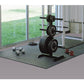 Warrior rubber gym floor mat in dark gray, shown in home gym setting with weight plates, barbell, dumbbells and rack