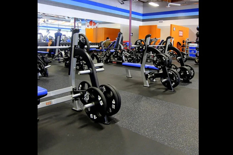 Warrior rubber gym flooring in dark gray, installed in fitness facility with exercise equipment and orange storage boxes visi
