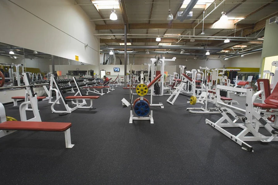 Warrior black rubber gym flooring installed in fitness facility with weight machines and equipment