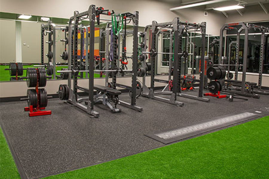 Warrior Sports Performance Turf bright green synthetic turf with gray rubber gym flooring in fitness facility with weight equ