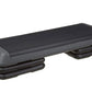 Black aerobic stepper platform with gray padded top and adjustable risers on white background