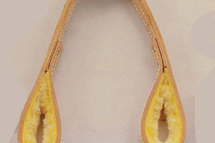 Tan and yellow sheep skin tricep pull with padded handles, flat lay on beige background