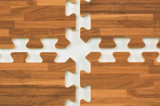 Brown wood grain interlocking foam floor tiles with white puzzle-piece edges, flat lay on wood surface