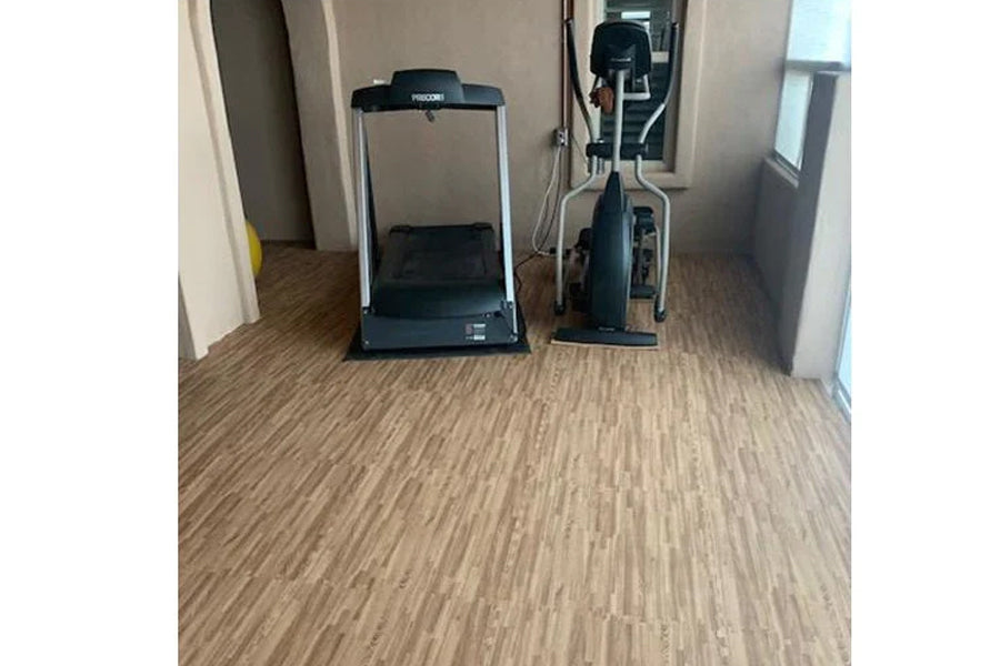 Warrior Wood Grain Interlocking Gym Flooring Tiles in light tan wood pattern installed in fitness room with treadmill and exe