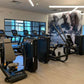 Warrior brand interlocking gym flooring tiles in wood grain pattern installed in fitness facility with exercise equipment