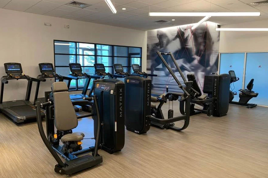 Warrior brand interlocking gym flooring tiles in wood grain pattern installed in fitness facility with exercise equipment