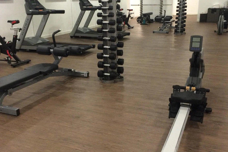 Warrior wood grain interlocking gym flooring tiles in brown, displayed in fitness studio with gym equipment