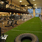 Warrior Workout Turf green artificial turf with white yard line markings and embedded tire, displayed in fitness facility