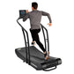 Man running on black Woodway Curve treadmill with curved running surface and digital display console, worn on white backgroun