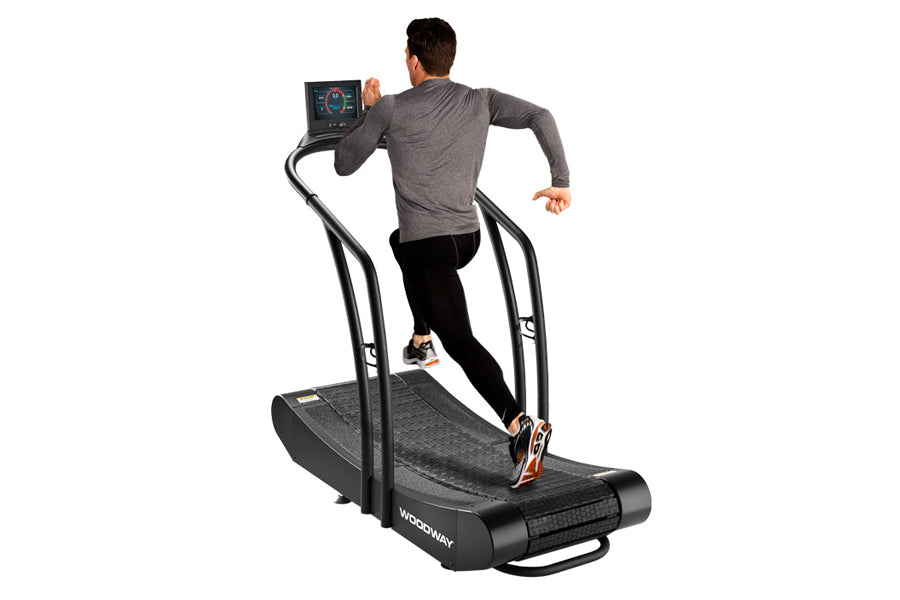 Man running on black Woodway Curve treadmill with curved running surface and digital display console, worn on white backgroun