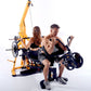 Two people using yellow and black Powertec WorkBench multi-station gym equipment with weight plates, demonstrating curl and l