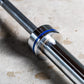 York Men's Elite Competition Olympic barbell with chrome finish, blue collar ring, and black shaft on concrete surface