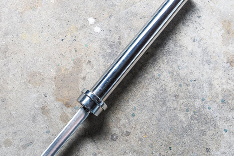 York Elite Power Bar in polished chrome with knurled grip section, flat lay on concrete surface