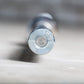 Silver metal barbell end cap with circular center detail, close-up view on white surface